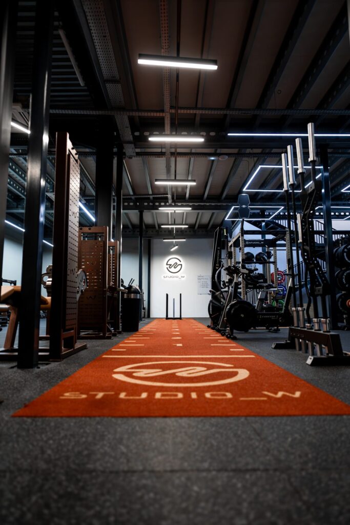 Piste de cross-training orange avec logo Studio W au sol dans la salle de sport